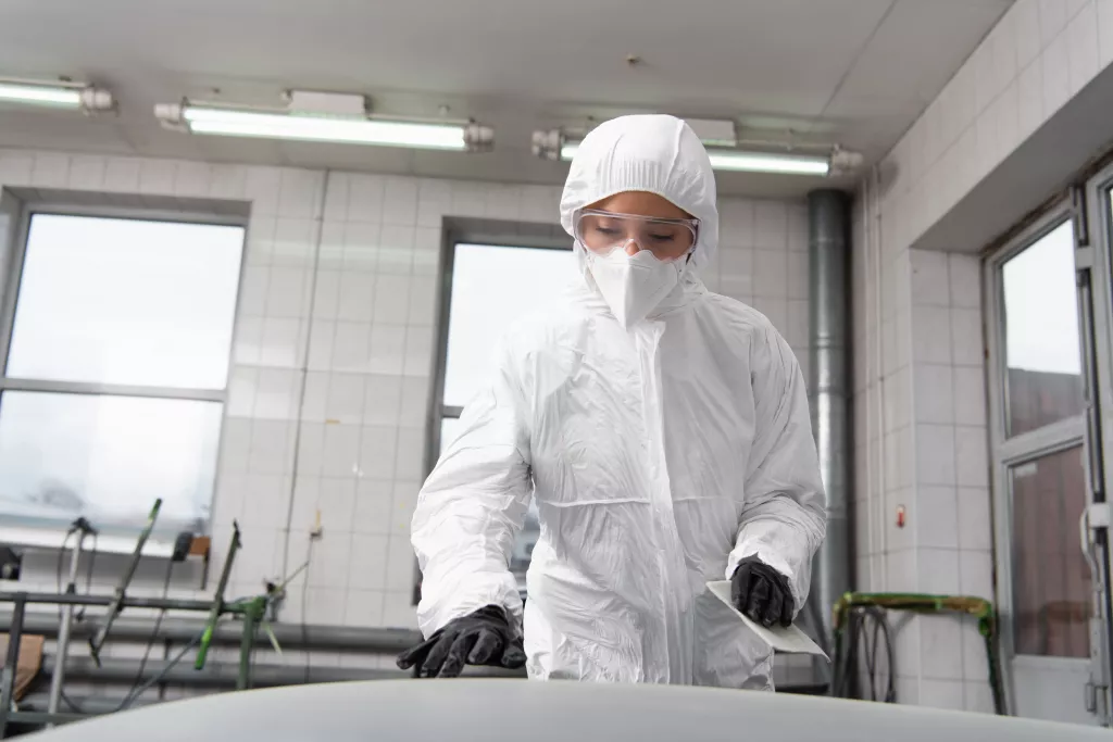 cleanteam-Fachkraft in Schutzkleidung und Haube bei der Reinraumreinigung in einer pharmazeutischen Produktionsanlage